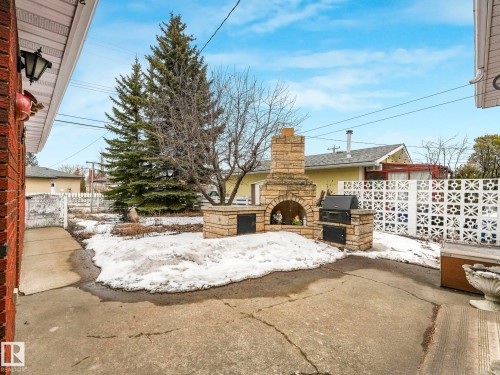 The property includes a paved patio area with a stone outdoor fireplace and an integrated grill - 5904 84 Avenue, Edmonton, AB - Outdoor