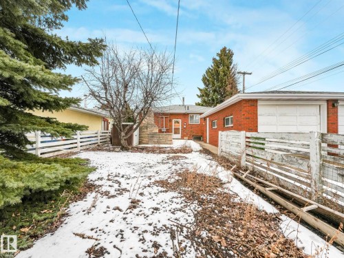 The property features a brick exterior, a garage with a white door, and a white fence - 5904 84 Avenue, Edmonton, AB - Outdoor