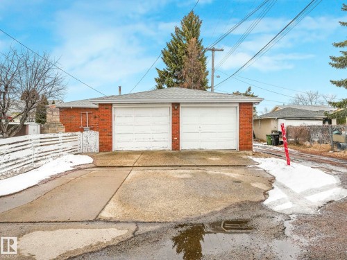 The property features a two-car garage with white doors and a brick exterior - 5904 84 Avenue, Edmonton, AB - Outdoor