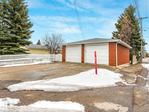 Detached brick garage with two white garage doors and a grey shingled roof - 5904 84 Avenue, Edmonton, AB - Outdoor