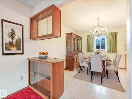 The dining area features a chandelier, tiled flooring, and a window with curtains - 5904 84 Avenue, Edmonton, AB - Indoor Photo Showing Dining Room
