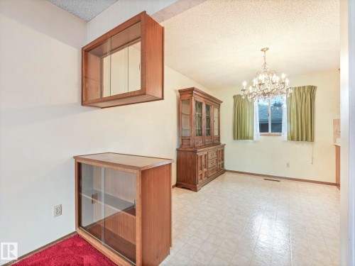 Dining area featuring a window with curtains, an ornate chandelier, and tiled flooring - 5904 84 Avenue, Edmonton, AB - Indoor Photo Showing Other Room