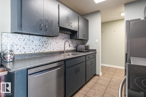 Kitchen with dark countertops, stainless steel appliances, tasteful backsplash, light tile patterned flooring, and gray cabinets - 1207 12303 Jasper Avenue, Edmonton, AB - Indoor