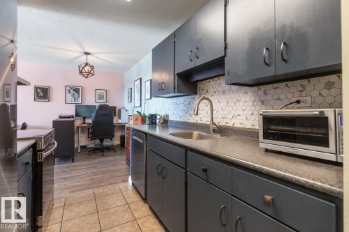 Kitchen featuring an office area, dark countertops, gray cabinets, stainless steel appliances, and backsplash - 1207 12303 Jasper Avenue, Edmonton, AB - Indoor Photo Showing Kitchen
