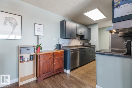 Kitchen featuring decorative backsplash, dishwasher, a textured ceiling, light wood finished floors, and dark countertops - 1207 12303 Jasper Avenue, Edmonton, AB - Indoor Photo Showing Kitchen