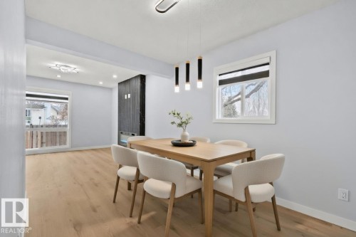 The property features light wood flooring throughout, light grey walls, and a modern light fixture - 8620 38A Avenue, Edmonton, AB - Indoor Photo Showing Dining Room