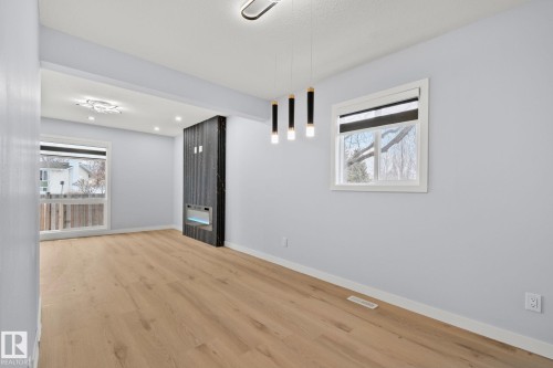 This living space features light wood flooring, light-colored walls, and a modern fireplace with an electric insert - 8620 38A Avenue, Edmonton, AB - Indoor Photo Showing Other Room