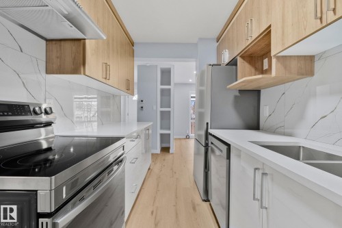 The kitchen features light wood cabinetry, white countertops, and stainless steel appliances, including a range, refrigerator, and dishwasher - 8620 38A Avenue, Edmonton, AB - Indoor Photo Showing Kitchen With Upgraded Kitchen