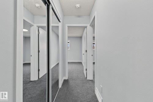 Hallway featuring light grey walls, dark grey carpet, and white trim - 8620 38A Avenue, Edmonton, AB - Indoor Photo Showing Other Room