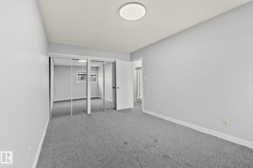 Bedroom featuring light gray walls, gray carpet, a ceiling light fixture, and mirrored closet doors - 8620 38A Avenue, Edmonton, AB - Indoor Photo Showing Other Room