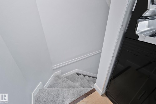 The property features a staircase with light grey carpeting, white baseboards, and a light-colored wall - 8620 38A Avenue, Edmonton, AB - Indoor Photo Showing Other Room