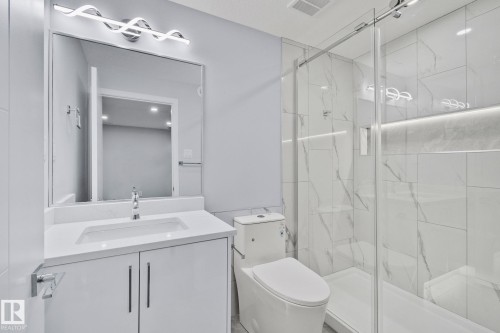 Modern bathroom featuring a vanity with a white countertop, a rectangular sink, and a large mirror - 8620 38A Avenue, Edmonton, AB - Indoor Photo Showing Bathroom