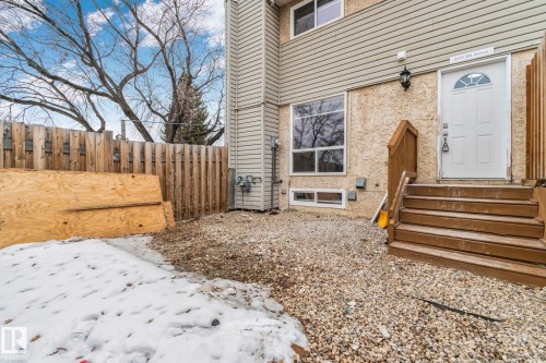 The property features a white exterior door, a brown wooden fence, and a gravel ground covering - 8620 38A Avenue, Edmonton, AB - Outdoor