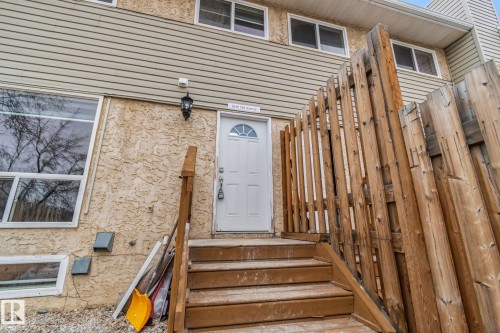 The property features a white paneled entry door with an arched window, a wooden staircase, and a wooden privacy fence - 8620 38A Avenue, Edmonton, AB - Outdoor