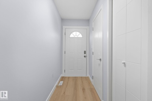 The property features light wood flooring, a white entry door with an arched window, and smooth light-colored walls - 8620 38A Avenue, Edmonton, AB - Indoor Photo Showing Other Room