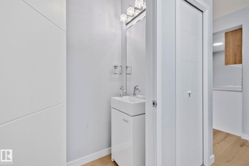 A modern bathroom featuring a white vanity with an integrated rectangular sink, a wall-mounted mirror, and a contemporary light fixture - 8620 38A Avenue, Edmonton, AB - Indoor