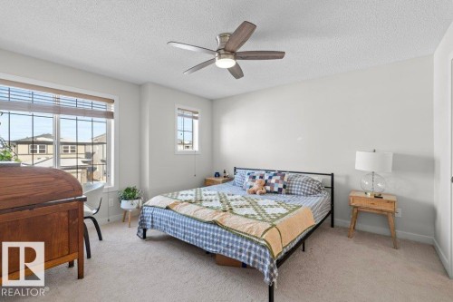 The property features a bedroom with light-colored carpeting, a ceiling fan, and window blinds - 1227 Secord Landing, Edmonton, AB - Indoor Photo Showing Bedroom