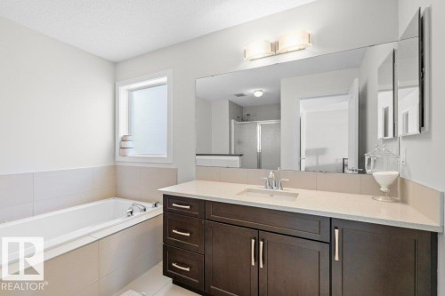 Bathroom featuring a vanity with a light-colored countertop, dark wood cabinetry, and a large mirror with overhead lighting - 1227 Secord Landing, Edmonton, AB - Indoor Photo Showing Bathroom