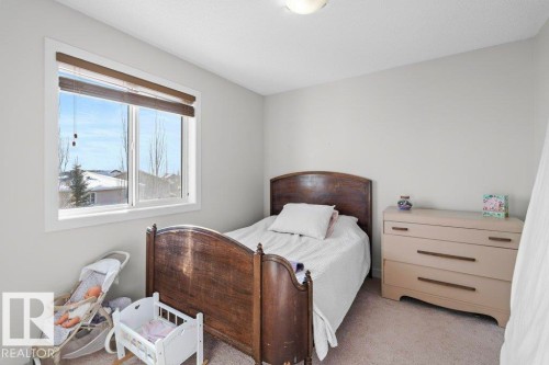 This bedroom features a window with blinds, carpeted flooring, and neutral wall paint - 1227 Secord Landing, Edmonton, AB - Indoor Photo Showing Bedroom