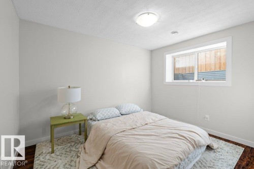 This room features light-colored walls, a window providing natural light, and dark-toned flooring partially covered by a patterned rug - 1227 Secord Landing, Edmonton, AB - Indoor Photo Showing Bedroom