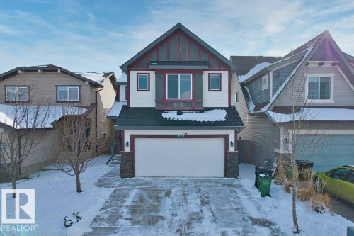 The property features a two-story exterior with a double garage, a paved driveway, and a front yard with trees - 1227 Secord Landing, Edmonton, AB - Outdoor With Facade