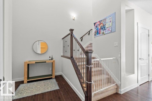 Inviting entryway featuring dark hardwood flooring, light grey walls, and a staircase with a dark wood banister and carpeted steps - 1227 Secord Landing, Edmonton, AB - Indoor Photo Showing Other Room
