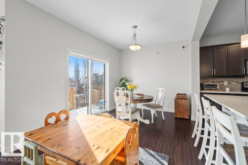 The dining area features dark hardwood flooring, a ceiling-mounted light fixture, and large sliding glass doors providing access to the outdoors - 1227 Secord Landing, Edmonton, AB - Indoor Photo Showing Dining Room