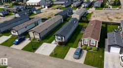 Aerial view of a residential community featuring a row of single-story homes with individual concrete driveways and manicured lawns - 