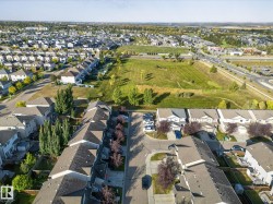 Aerial view showcasing the residential neighborhood with a variety of homes, green spaces, and paved roads - 