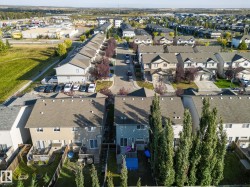 Aerial view of a residential area featuring multiple properties with pitched roofs and private yards - 