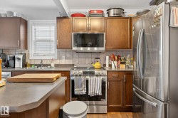 The kitchen features wood cabinetry, stainless steel appliances, and a tiled backsplash - 