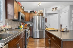 A well-appointed kitchen featuring wood cabinetry, stainless steel appliances, and a double sink - 