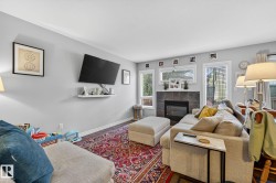 Living room featuring a dark tile fireplace with a mantel, light gray walls, and large windows with blinds - 