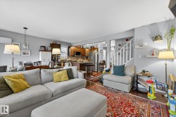 Living area featuring a light gray wall color, hardwood floors, and a staircase with white railings - 