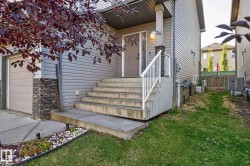 The property features a front entrance with concrete steps and a white railing, leading to a light-colored front door - 