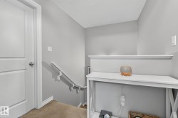 The property features a staircase with a white handrail, carpeted steps, and light gray walls - 