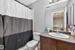 This bathroom features a vanity with a sink, a toilet, and a shower area with a curtain - 