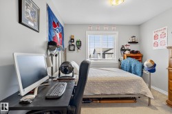 The room features a window providing natural light, light gray walls, and carpeted flooring - 