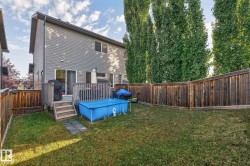 The property includes a fenced yard with a lawn, a wooden deck with stairs, and tall, mature trees along the perimeter - 