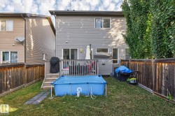 The property features a fenced yard with a lawn, a wooden deck with stairs, and a grey exterior - 