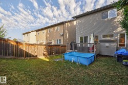 The property features a fenced backyard with a lawn and a wooden deck - 