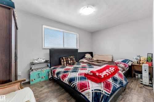The room features a window with blinds, light gray walls, and wood-look flooring - 12908 126 Street, Edmonton, AB - Indoor Photo Showing Bedroom