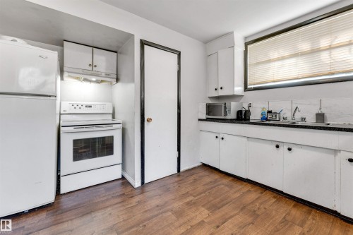 The kitchen features white cabinetry, a white electric range, and a white refrigerator - 12908 126 Street, Edmonton, AB - Indoor Photo Showing Kitchen