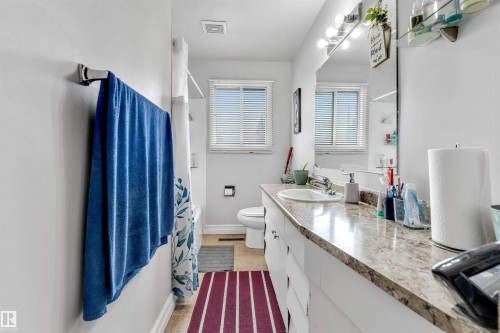 Bathroom featuring a spacious vanity with an integrated sink, a large mirror with overhead lighting, and natural light from the window - 12908 126 Street, Edmonton, AB - Indoor Photo Showing Bathroom
