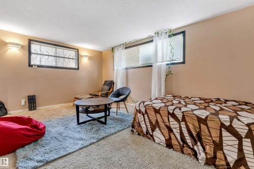 This versatile room features neutral-toned walls, carpeted flooring, and two windows allowing for natural light - 12908 126 Street, Edmonton, AB - Indoor Photo Showing Bedroom