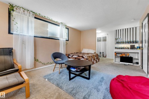 The interior features light-colored walls and carpeting, with a window fitted with blinds and sheer white curtains - 12908 126 Street, Edmonton, AB - Indoor