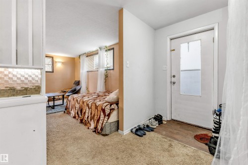 Entryway with a white door featuring a window, opening into a carpeted living space with a window - 12908 126 Street, Edmonton, AB - Indoor