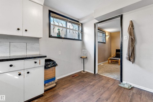 The property features white cabinetry with black countertops, a window, and wood-look flooring - 12908 126 Street, Edmonton, AB - Indoor Photo Showing Other Room