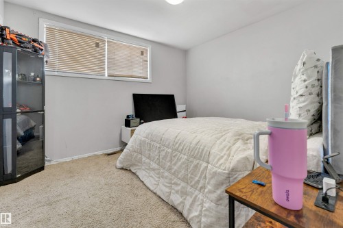 This bedroom features light-colored walls, carpeted flooring, and a window with blinds - 12908 126 Street, Edmonton, AB - Indoor Photo Showing Bedroom