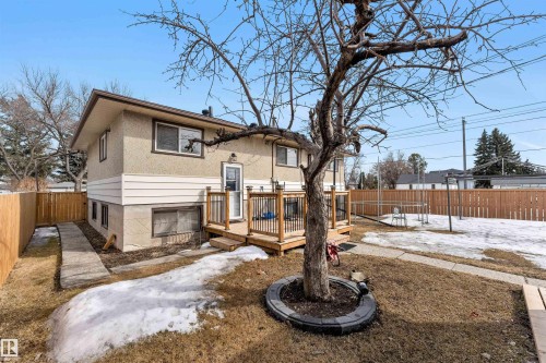 The property features a stucco exterior, a wooden deck with railing, and a fenced yard - 12908 126 Street, Edmonton, AB - Outdoor
